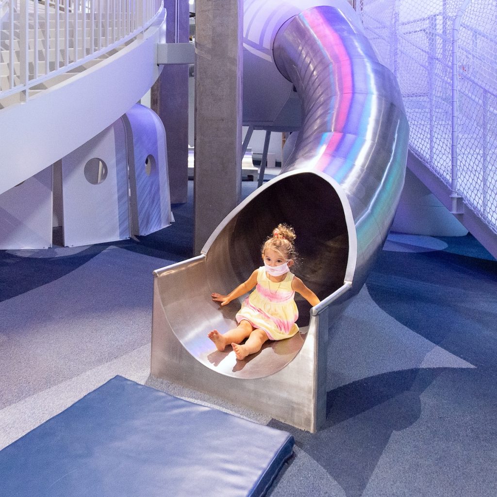 Little girl coming down the toddler Dream Machine slide