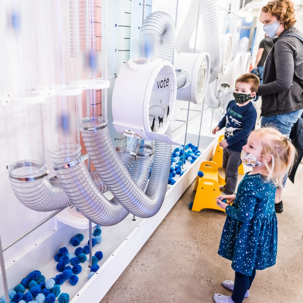 Little girl and boy at Pom Pom Poll in the Data Science Alley exhibit.